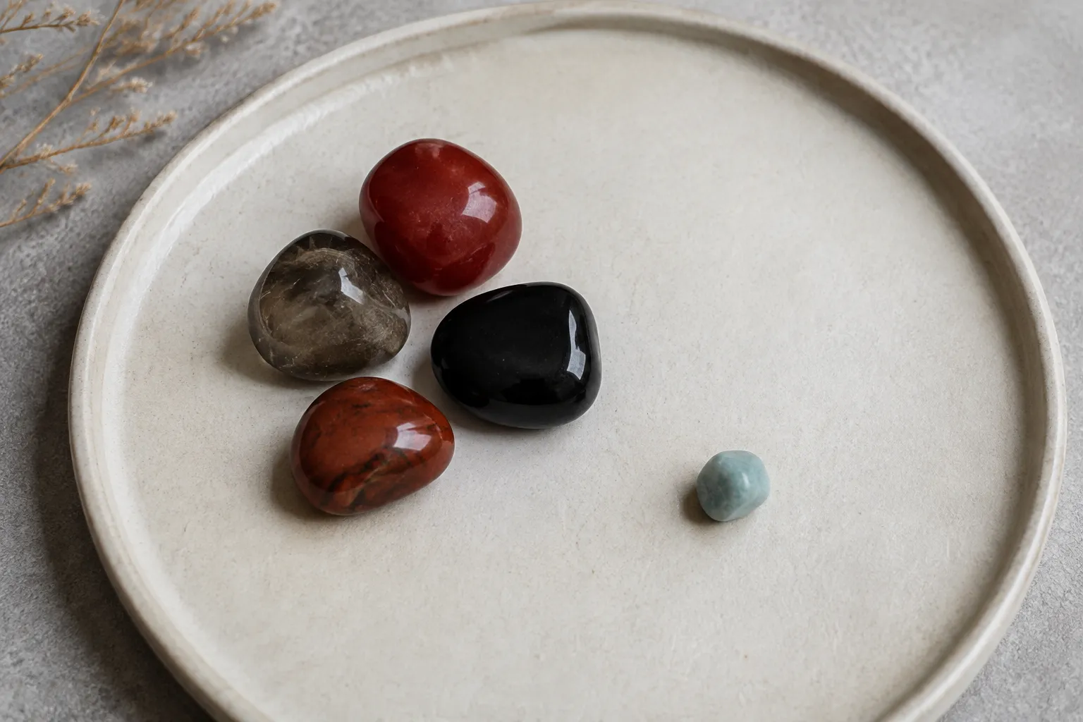 A small blue-green accent stone placed off center near red brown smoky and black root chakra stones